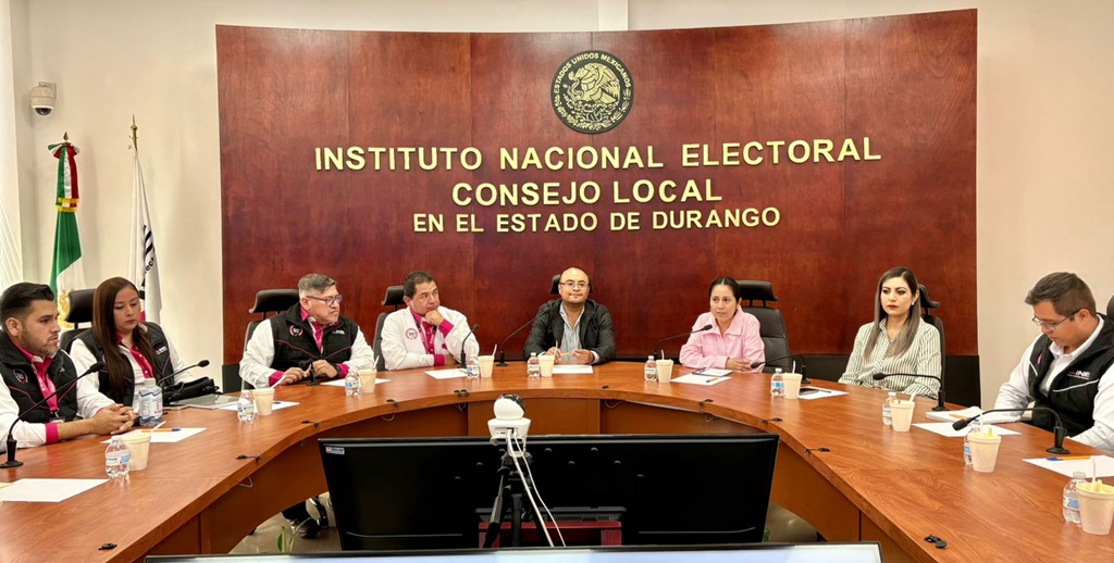 varias personas con chaleco negro sentadas alrededor de una mesa ovalada