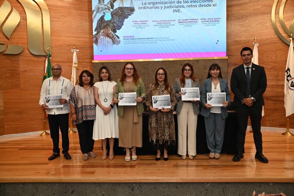 seis mujeres y dos hombres de pie sostienen diplomas