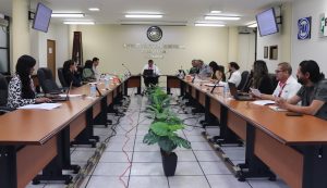 varias personas sentadas alrededor de una mesa semi-ovalada