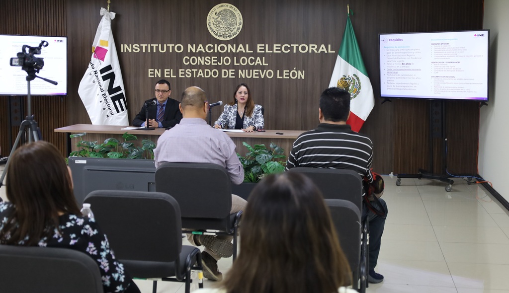 dos personas hablando frente a personas sentadas