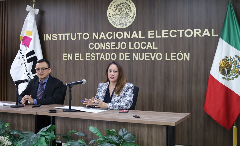 una mujer y un hombre sentados frente a una mesa con micrófono