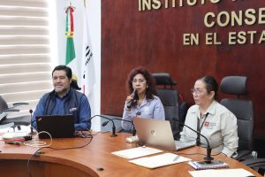 tres personas sentada frente a una mesa con micrófonos