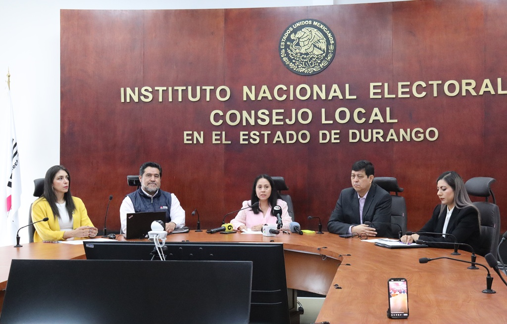 cinco personas sentadas en una mesa ovalada de madera