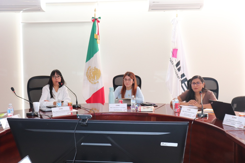 tres mujeres sentadas en una mesa ovalada