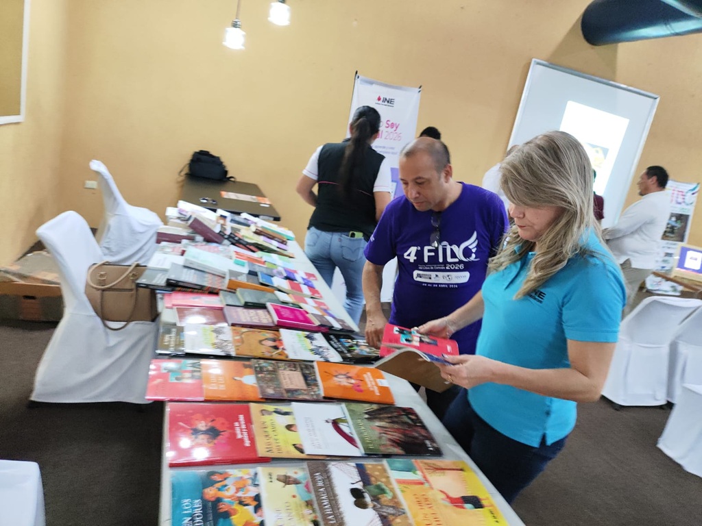 una mujer y un hombre observando una mesa con libros de colores
