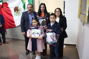 tres personas adultas y dos menores que sostienen unos libros del INE