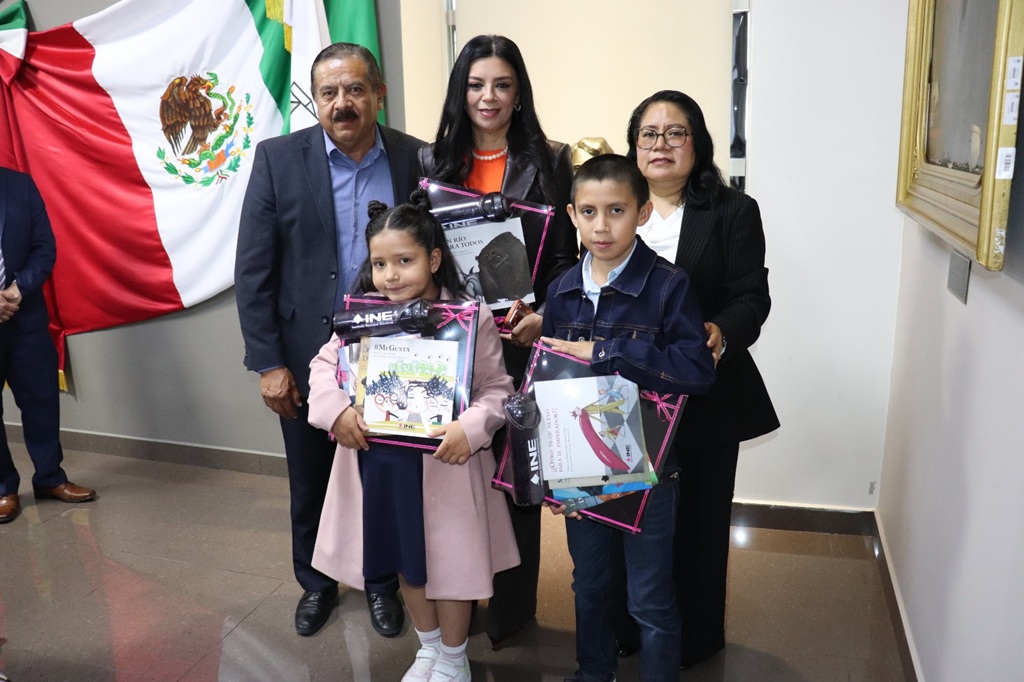 tres personas adultas y dos menores que sostienen unos libros del INE