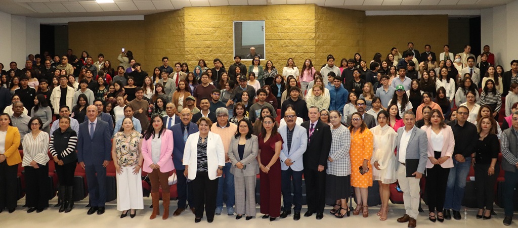 muchas personas de pie en un auditorio posando para la foto oficial
