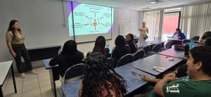 una persona de pie hablando frente a personas sentadas