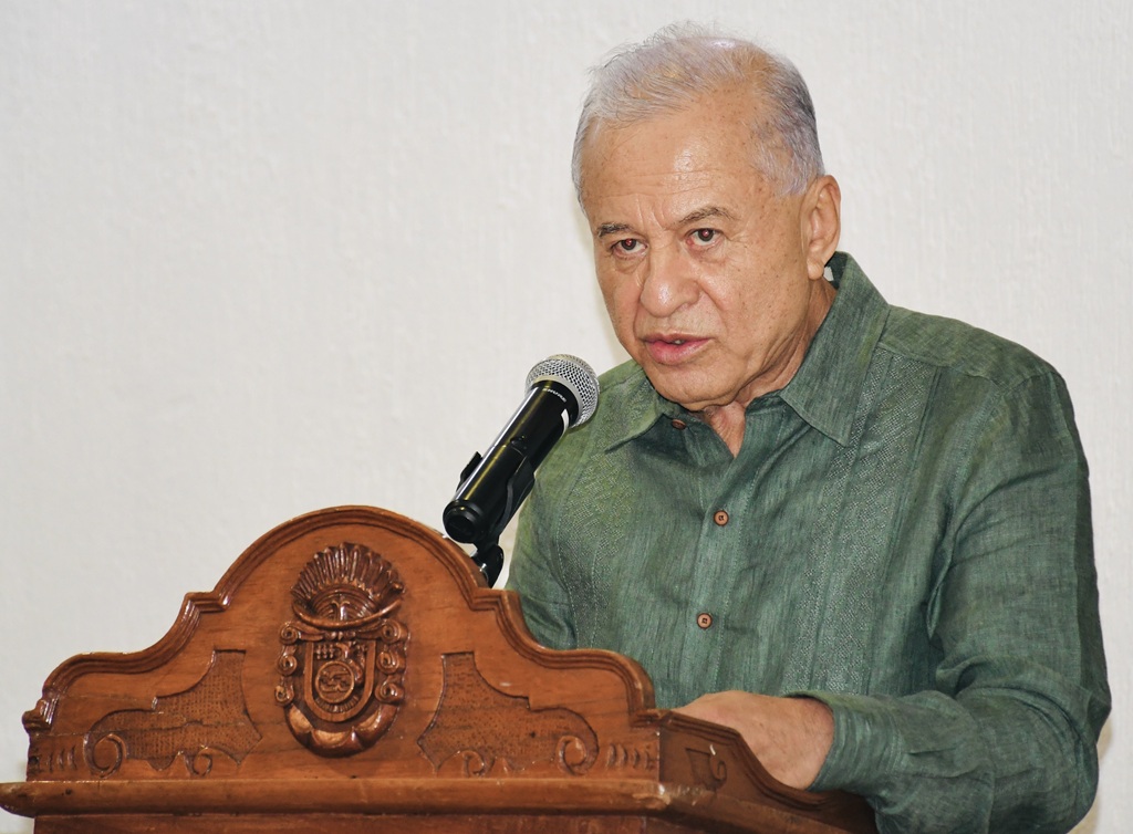 hombre cabello cano de pie hablando frente a un micrófono