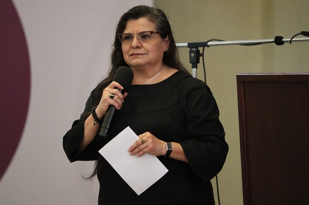 mujer cabello largo lacio de pie con un micrófono cerca de la boca