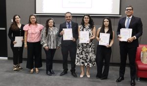 siete personas de pie, cuatro de ellas sostienen reconocimientos