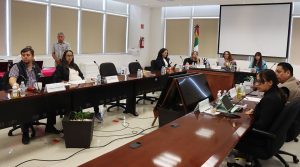 personas sentadas alrededor de una mesa ovalada de madera