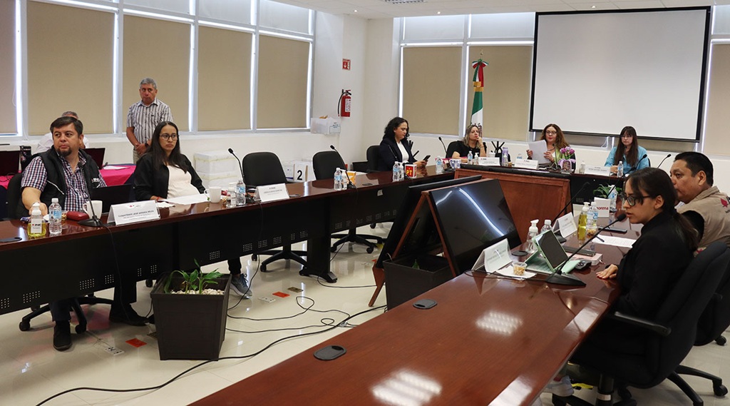 personas sentadas alrededor de una mesa ovalada de madera