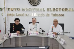 tres personas sentadas frente a una mesa ovalada