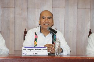 Un hombre sentado habla frente a un micrófono