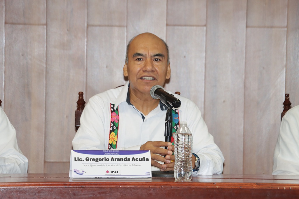 Un hombre sentado habla frente a un micrófono