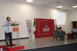 un hombre con guayabera de pie hablando frente a un atril