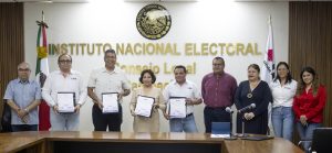 nueve personas de pie sosteniendo sus diplomas