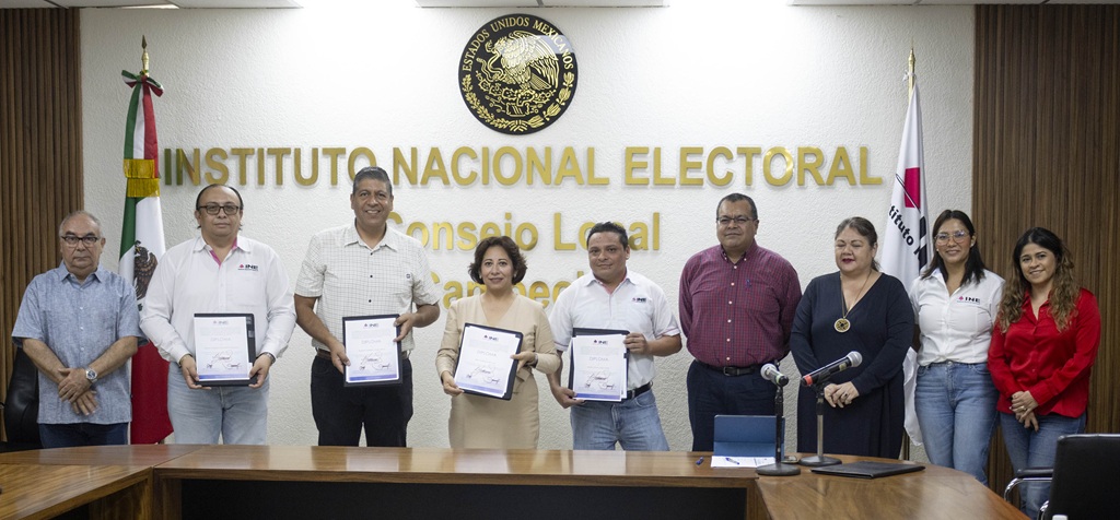 nueve personas de pie sosteniendo sus diplomas