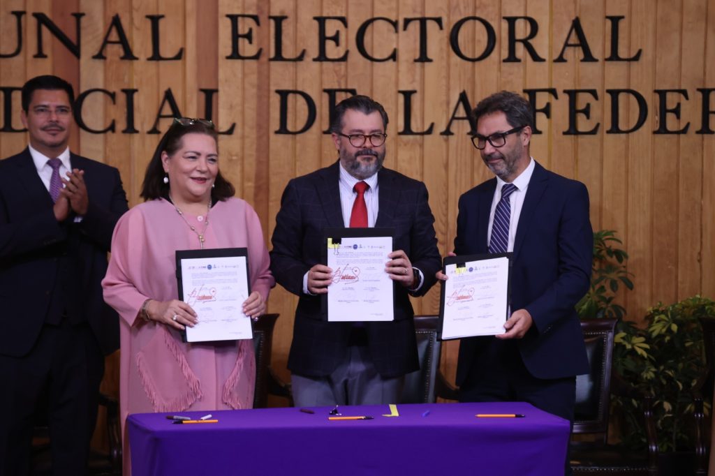 Personas participantes paradas en el estrado con el documento en la mano posado para la foto.