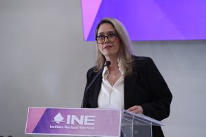 Consejera Electoral Frida Denisse Gómez Puga parada en el pódium del lobby del instituto.