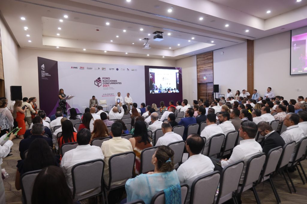 Personas participantes sentados en el estrado frete a los invitados.