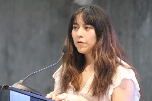 una mujer cabello largo hablando frente a un micrófono
