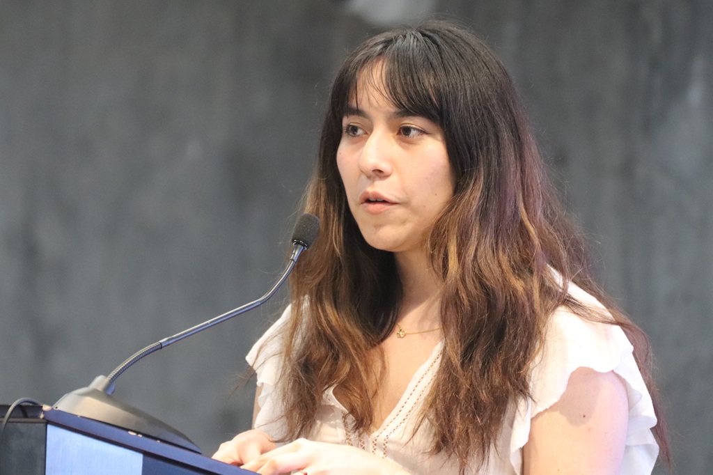 una mujer cabello largo hablando frente a un micrófono