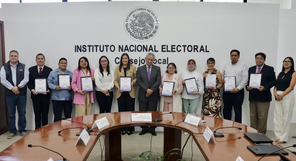 trece personas de pie, nueve sostienen diplomas