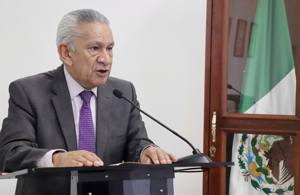 un hombre mayor de traje hablando frente a un micrófono