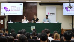 tres personas sentadas frente al público