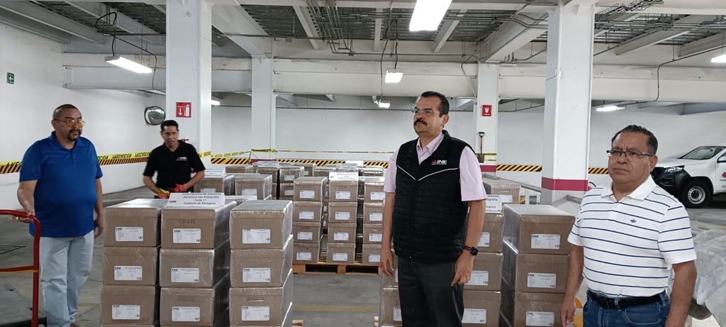 cuatro hombres parados a un costado de paquetes con cajas