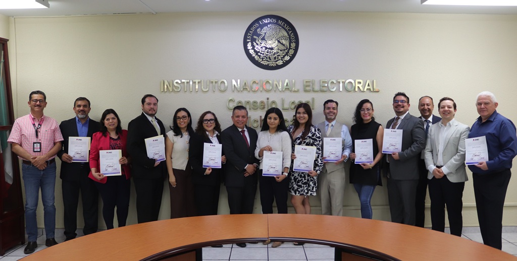 quince personas de pie sosteniendo sus diplomas