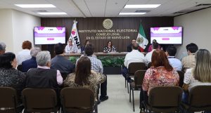 personas en un salón escuchando a otras personas sentadas al frente