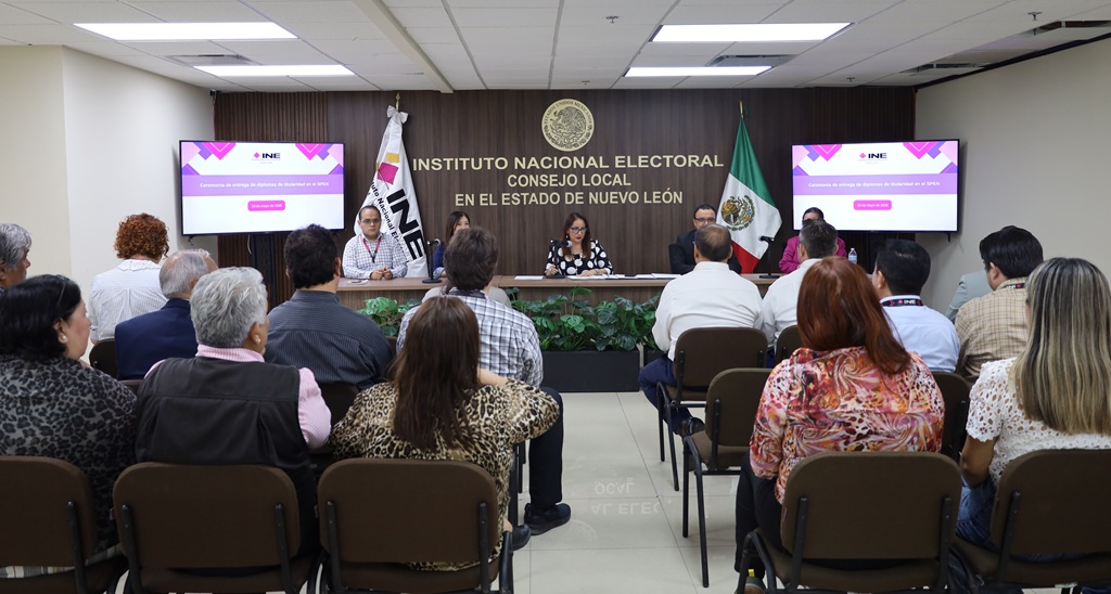 personas en un salón escuchando a otras personas sentadas al frente