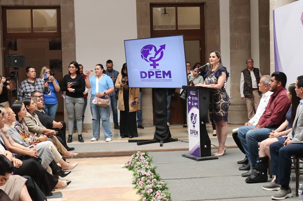 mujer hablando de pie frente a personas sentadas