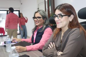 dos mujeres con lentes sentadas sonriendo