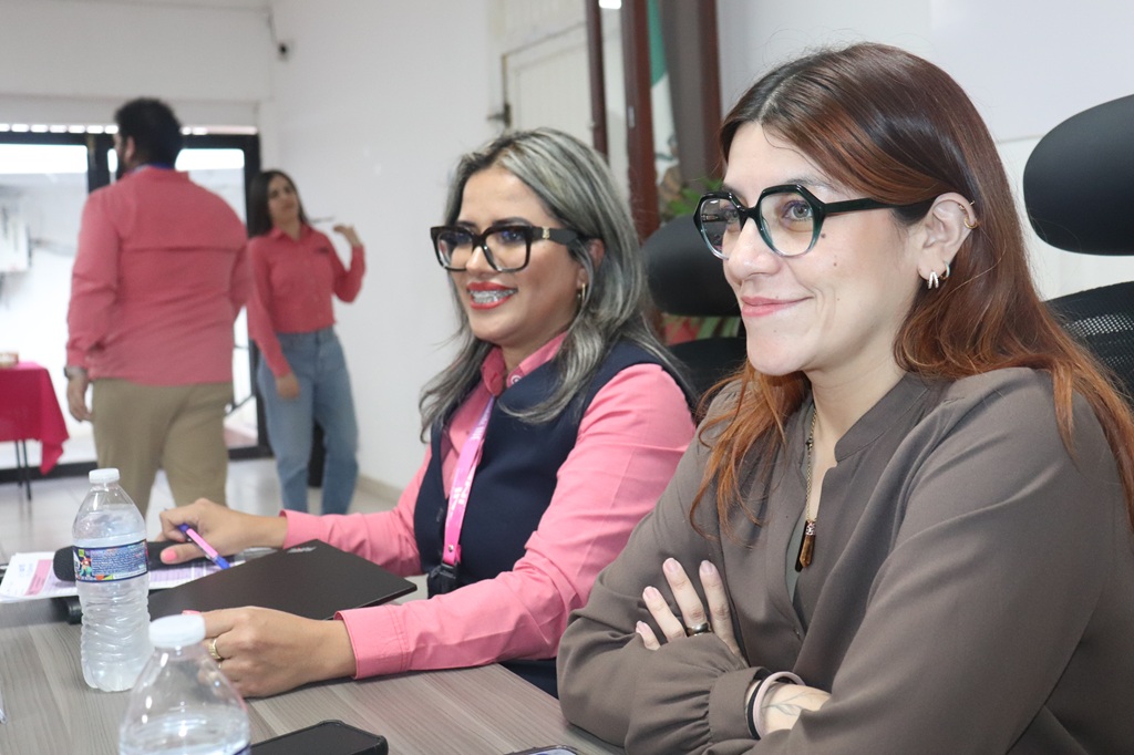dos mujeres con lentes sentadas sonriendo