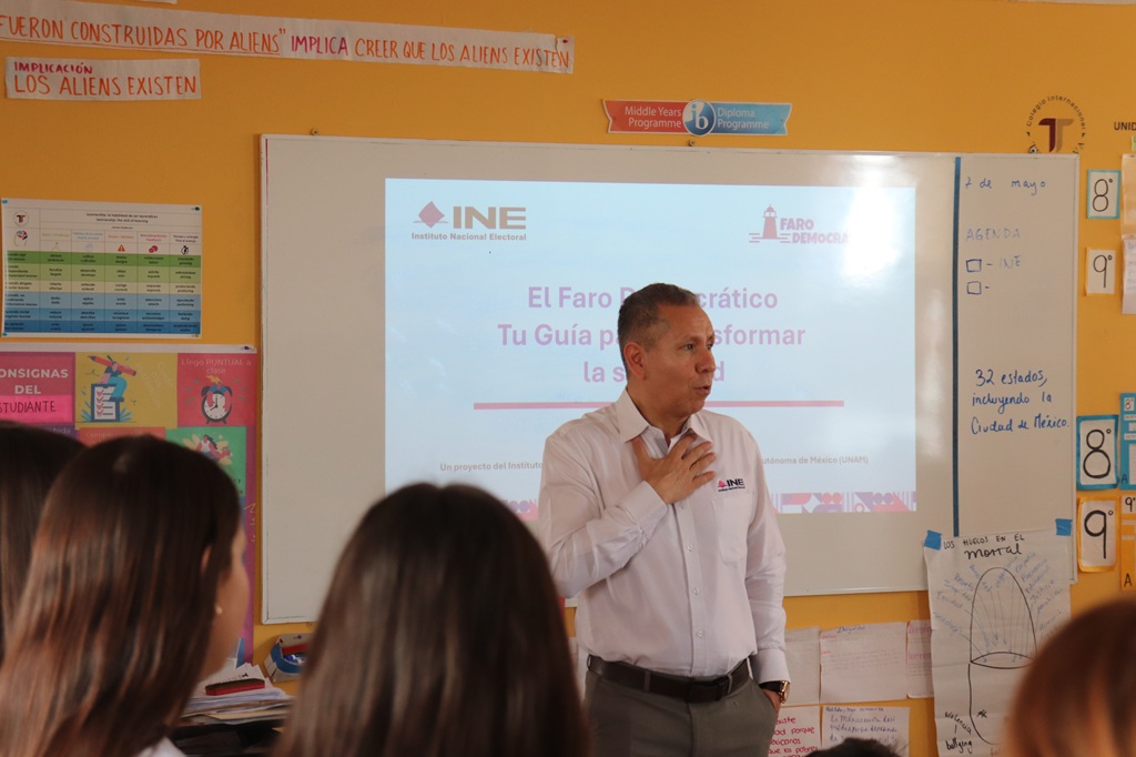un hombre de pie frente a un proyector de imágenes