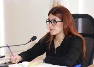 Mujer pelo rojizo sentada frente a un micrófono