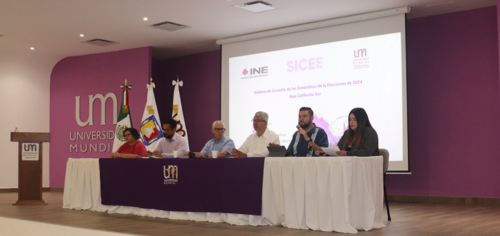 seis personas sentadas en una mesa frente a una pantalla de proyector