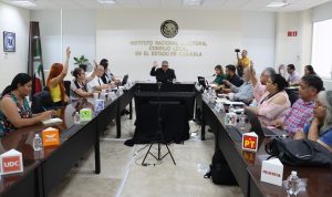 varias personas sentadas votando a mano alzada