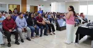 personas sentadas escuchando a una mujer que habla de pie a ellos