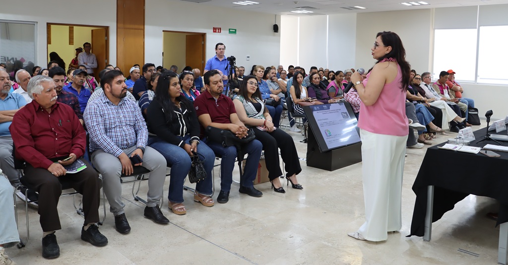 personas sentadas escuchando a una mujer que habla de pie a ellos
