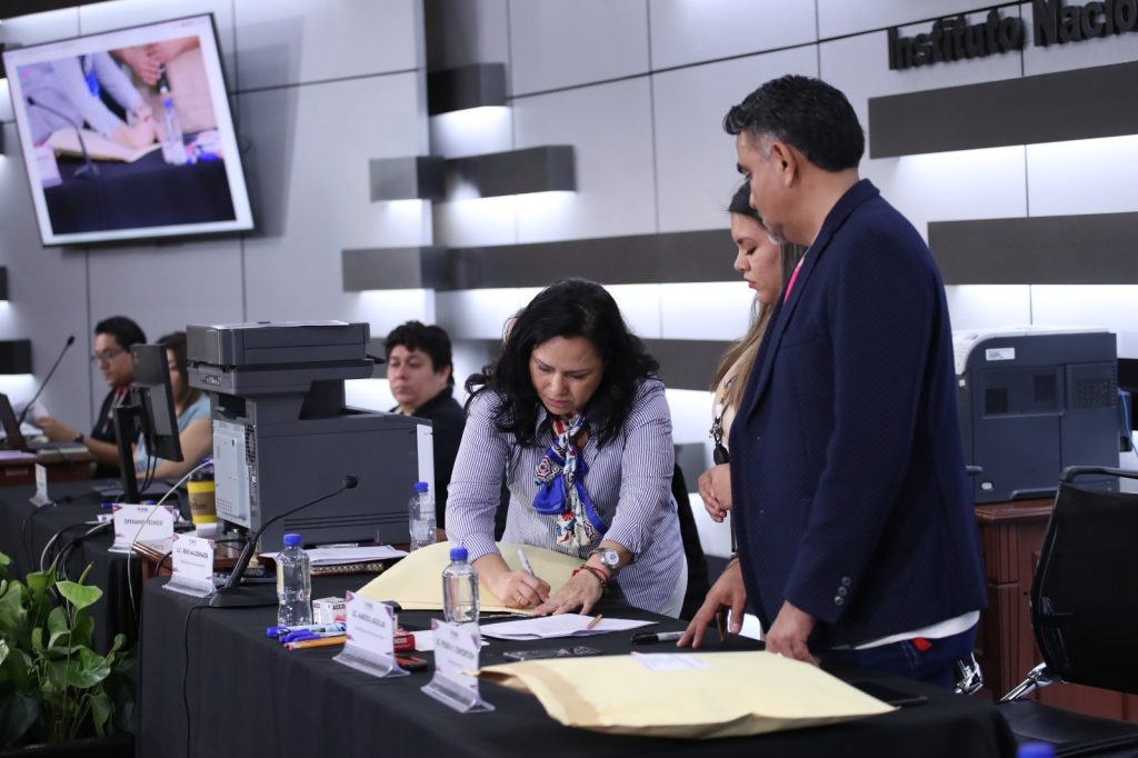 Personas sellando sobres con información de voto electrónico