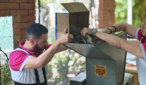 una persona vaciando contenido de una caja en una maquina trituradora