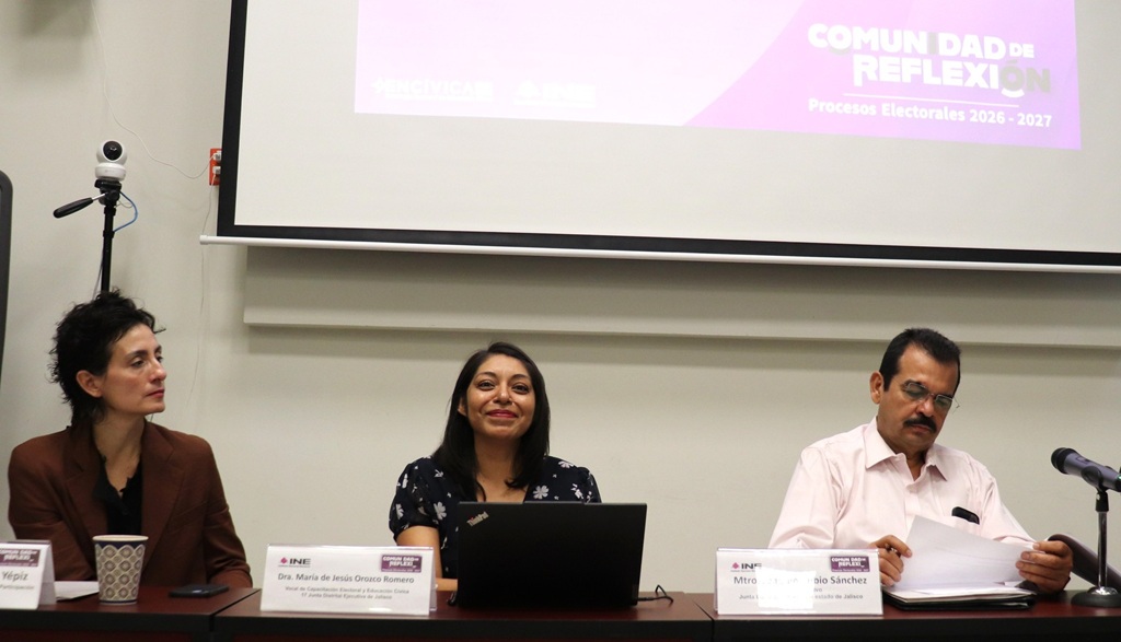 dos mujeres sentadas, a su lado un hombre leyendo
