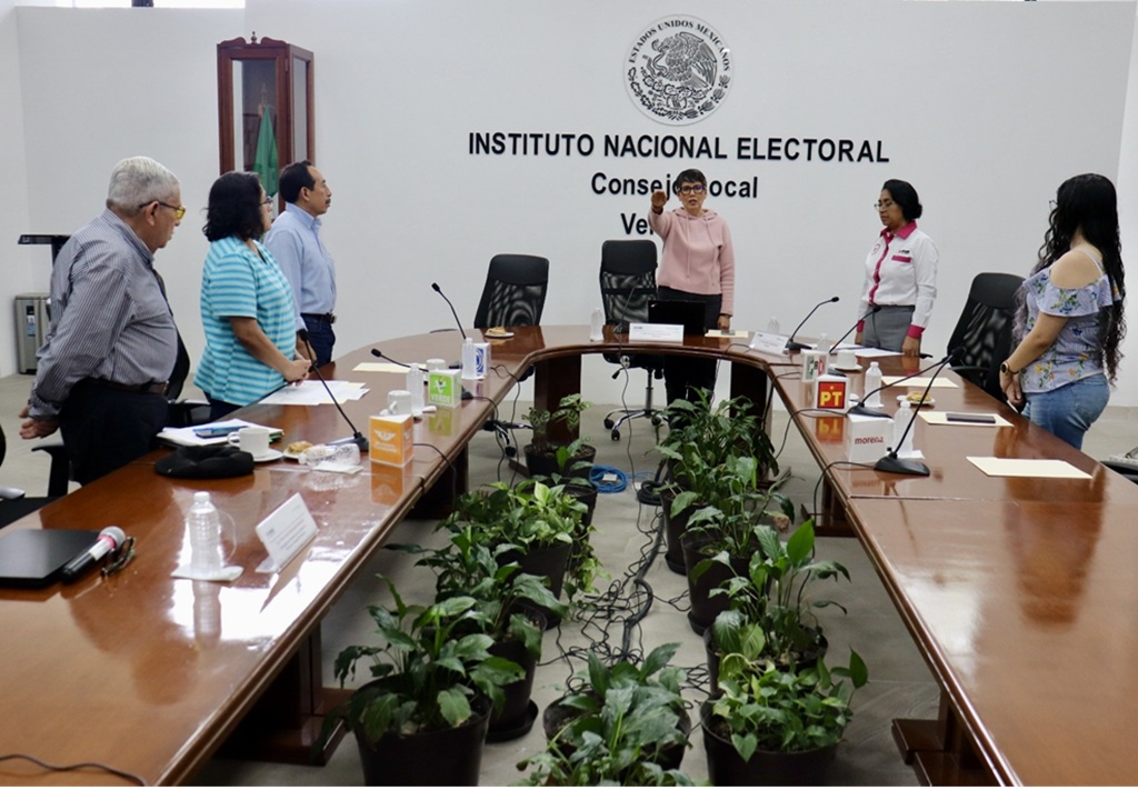 varias personas de pie, una de ellas con el brazo derecho extendido