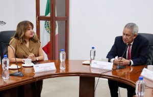 una mujer y un hombre sentados frente a una mesa con micrófonos